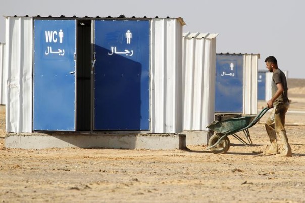 A Jordanian worker uses a wheelbarrow to transport materials for building the Azraq Syrian Refugee Camp, the third of its kind, near Al Azraq, 80km (50 miles) east of Amman