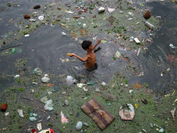 A boy wades through polluted waters in Ahmedabad, India, July 2013